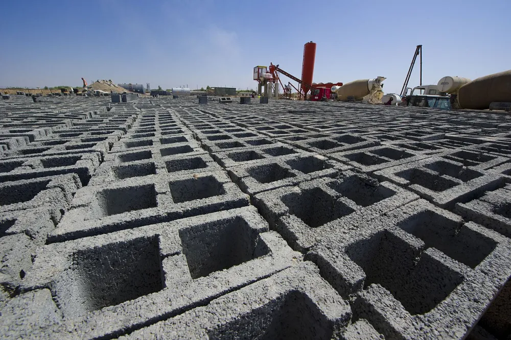 A wall built from grey hollow concrete blocks, showing the repeating pattern of stacked concrete masonry units
