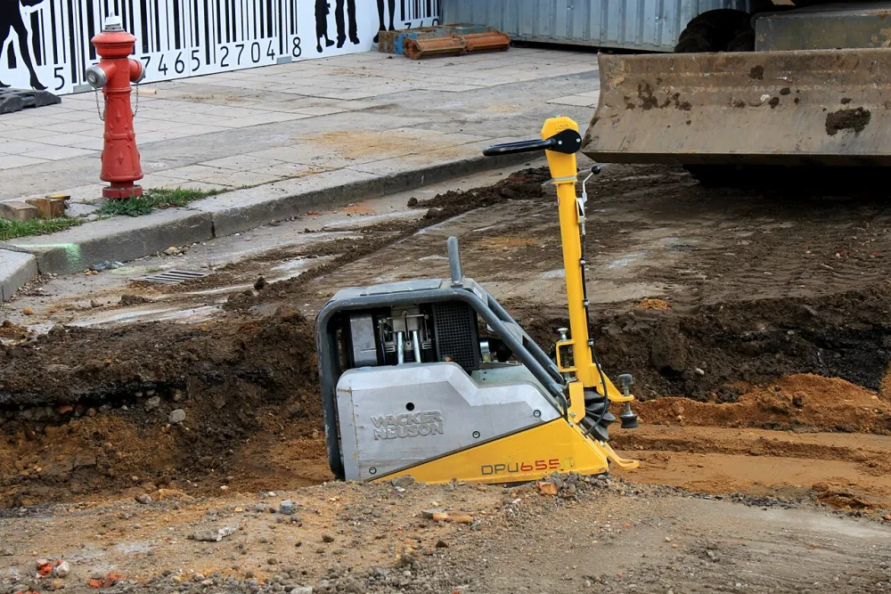 A vibrating plate compactor compacting crushed stone aggregate on a construction site